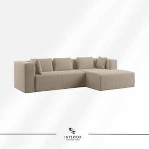 Minimalist L-shaped sofa upholstered in soft textured fabric, featuring clean lines, low-profile arms, and a spacious chaise extension in a warm neutral tone.