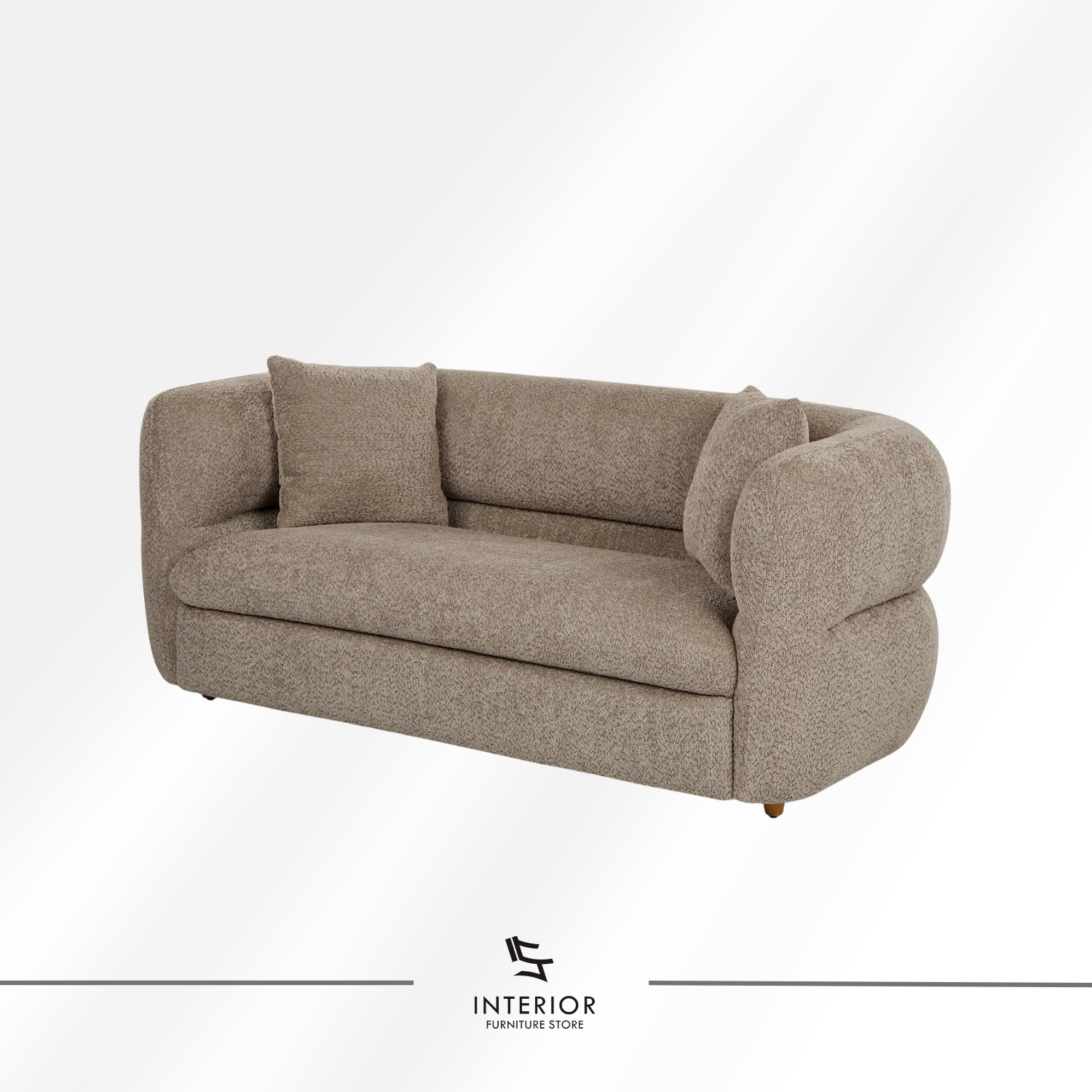 Curved upholstered sofa in warm beige fabric with a low backrest and rounded arms, complemented by two matching cushions.