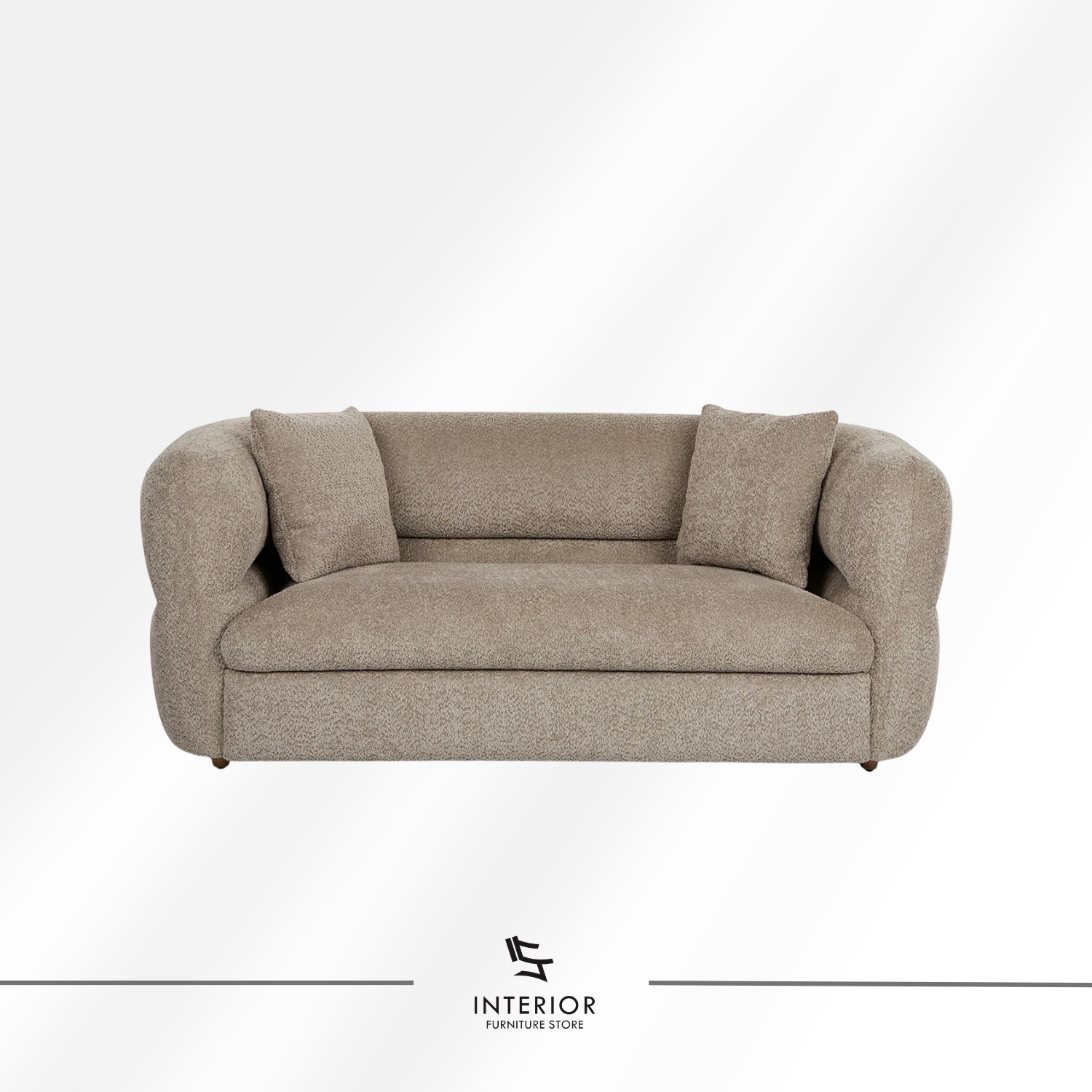 Curved upholstered sofa in warm beige fabric with a low backrest and rounded arms, complemented by two matching cushions.