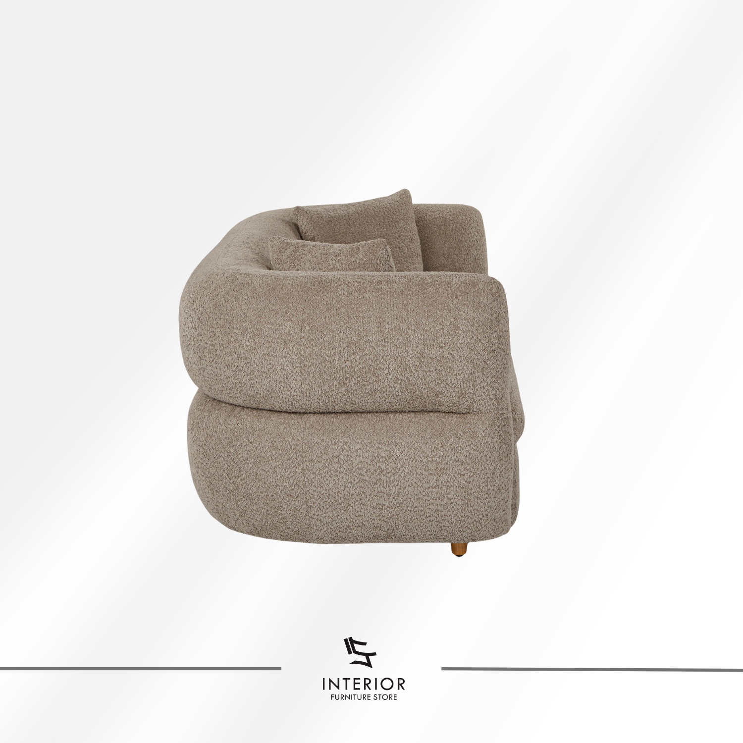 Curved upholstered sofa in warm beige fabric with a low backrest and rounded arms, complemented by two matching cushions.