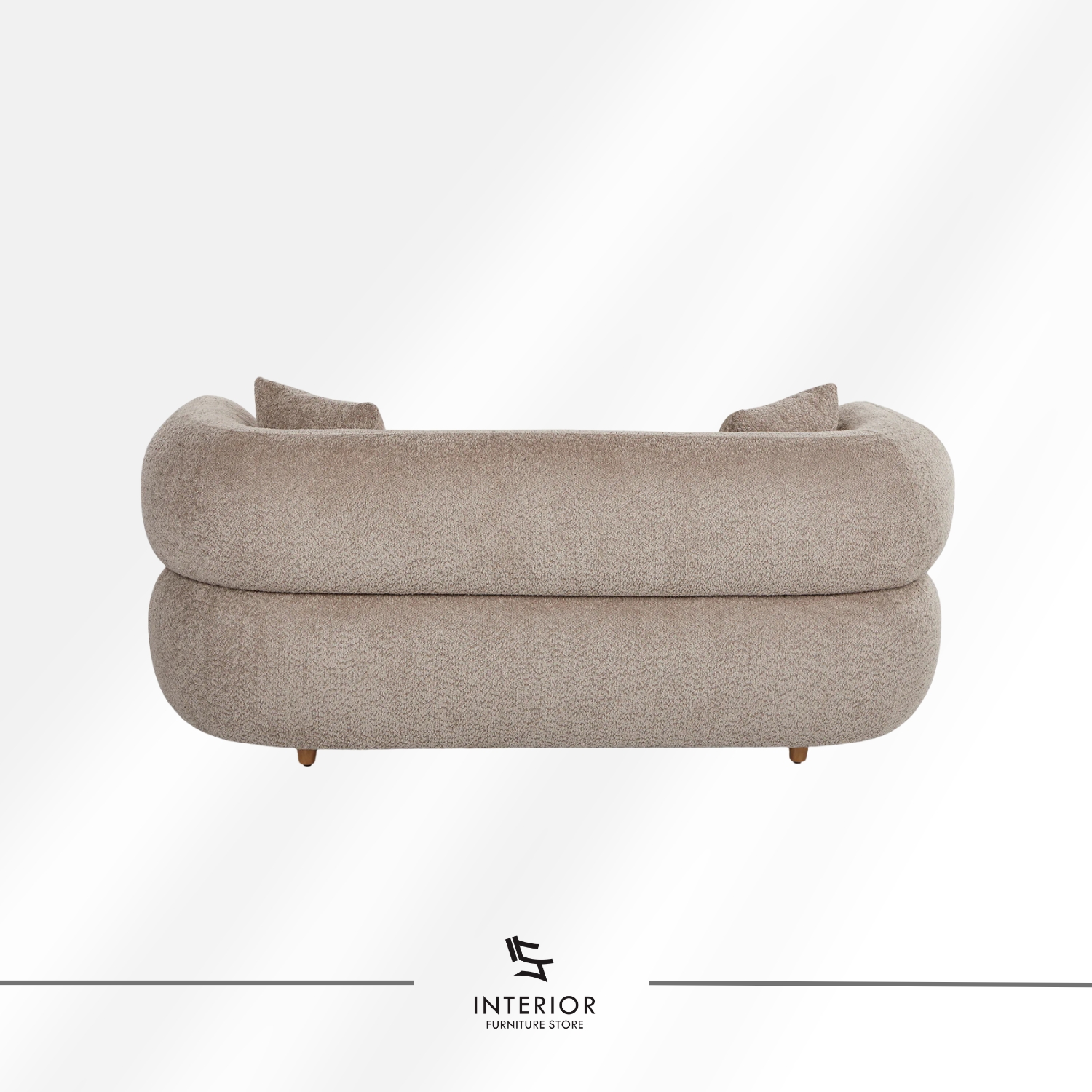 Curved upholstered sofa in warm beige fabric with a low backrest and rounded arms, complemented by two matching cushions.
