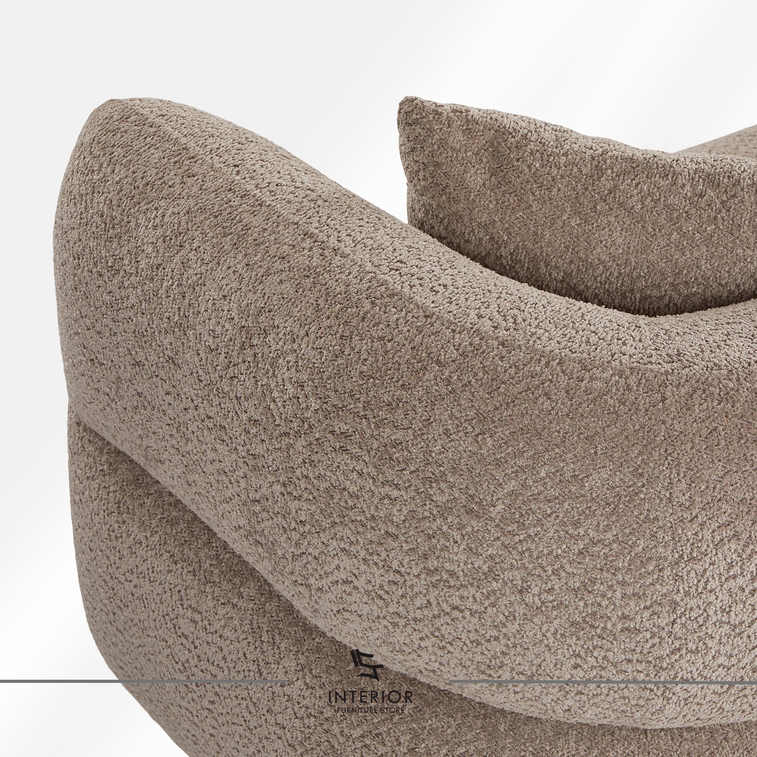 Curved upholstered sofa in warm beige fabric with a low backrest and rounded arms, complemented by two matching cushions.